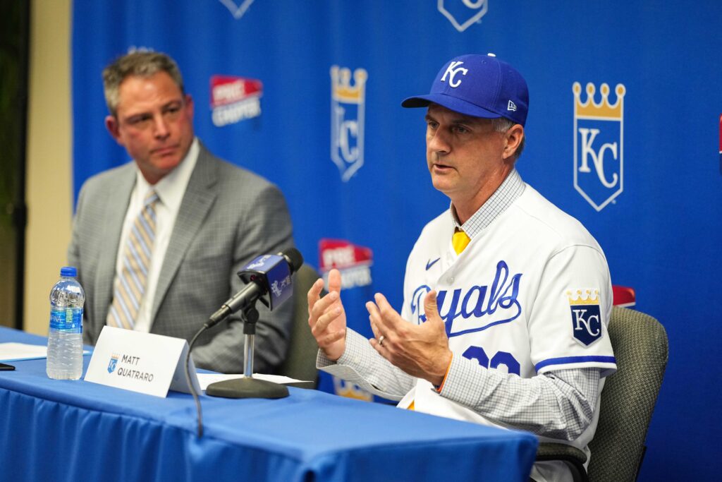 a man in a baseball uniform talking to another man in a suit